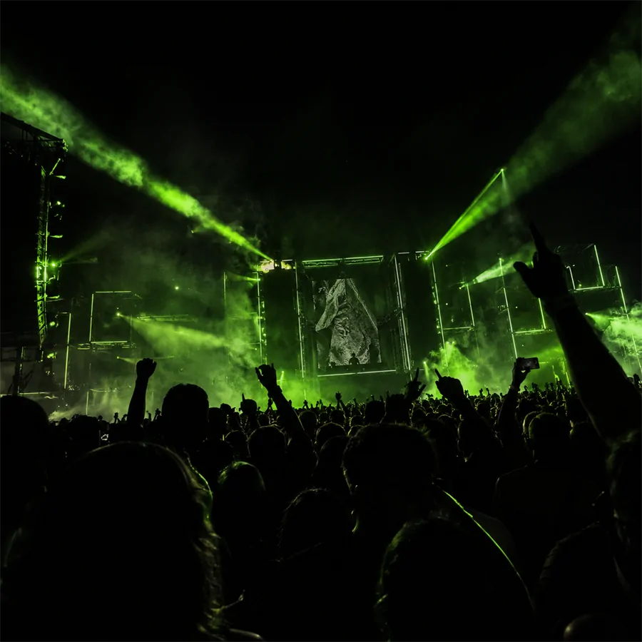 Público em festival de música eletrônica iluminado por luzes verdes